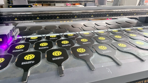 Industrial UV digital printer applying custom brand graphics and textured grit finish on paddle surfaces