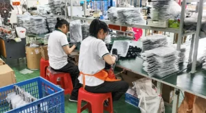 Workers handling pickleball paddles beside stacks of individually wrapped paddles